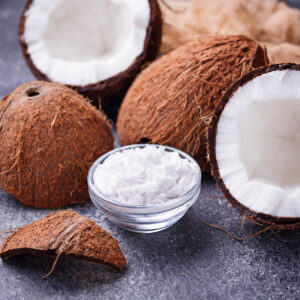 Coconuts cracked opened with a bowl of coconut pulp in the middle.