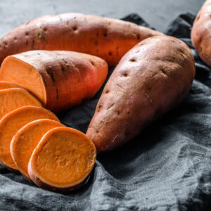 Raw sweet potatoes cut up and placed in a basket lined with a blue napkin.
