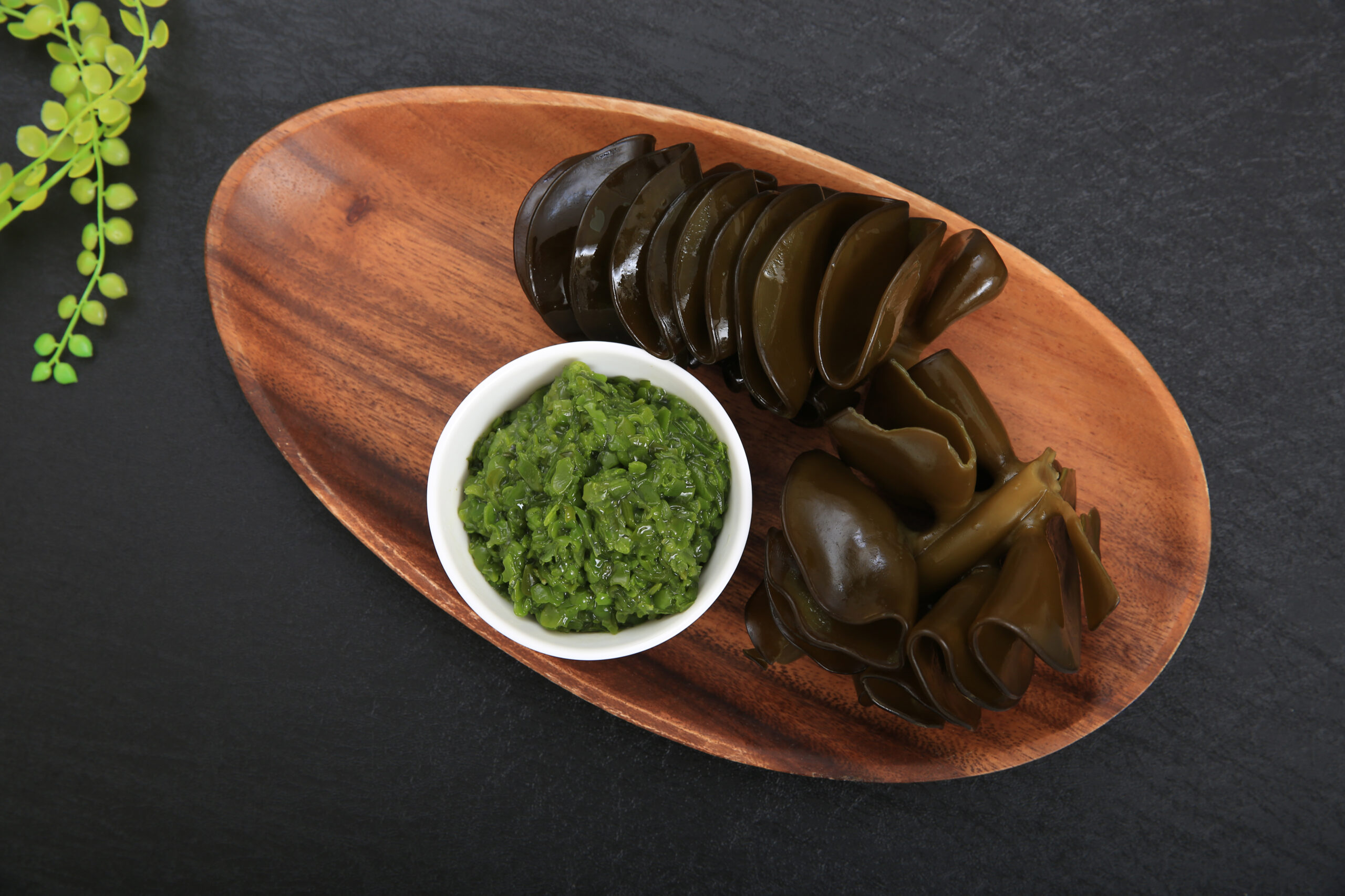 Seaweed and seaweed powder on a wooden dish on a dark gray background
