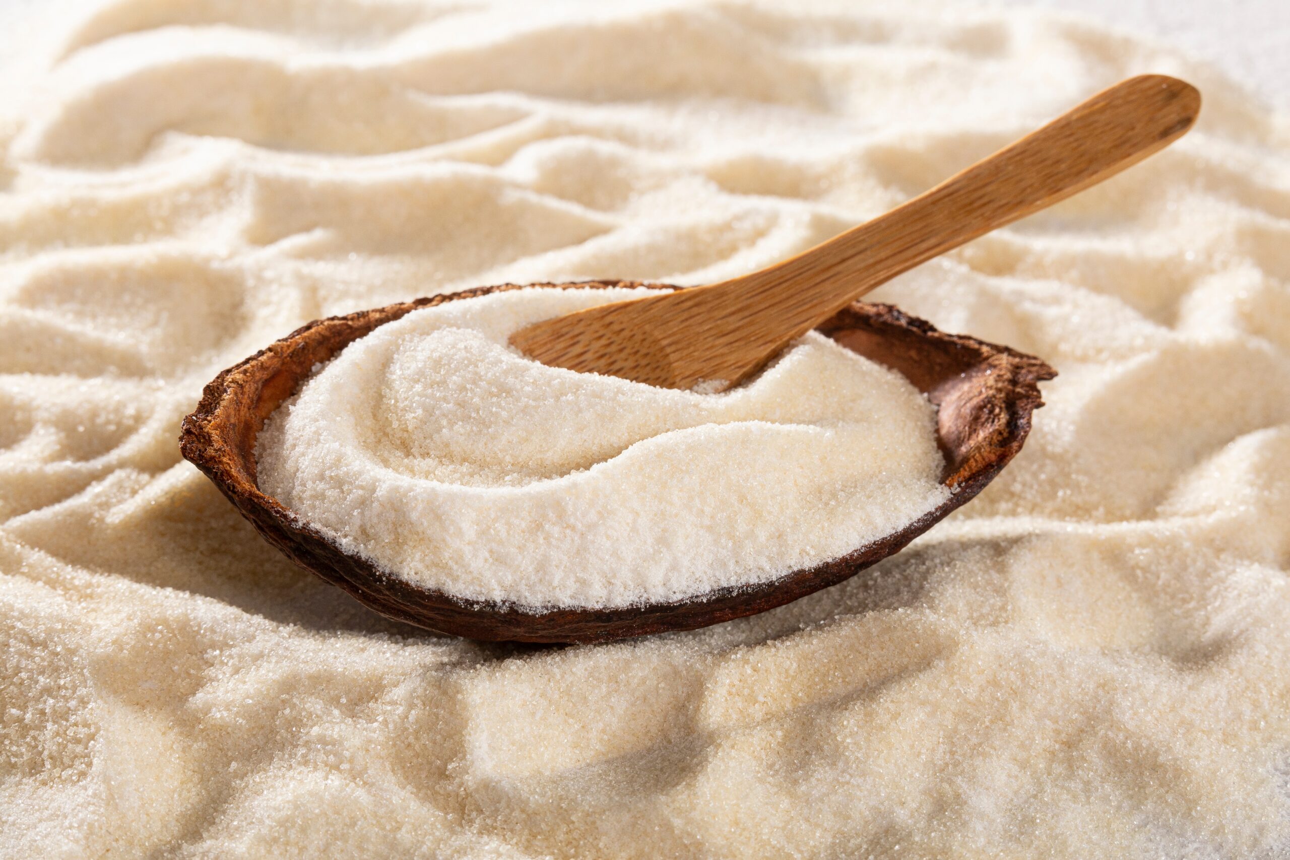 Collagen powder in a wooden dish, scooped by a wooden spoon.